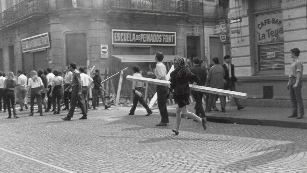 Una joven rosarina, participante activa de las protestas, corriendo con un palo de madera en sus brazos.