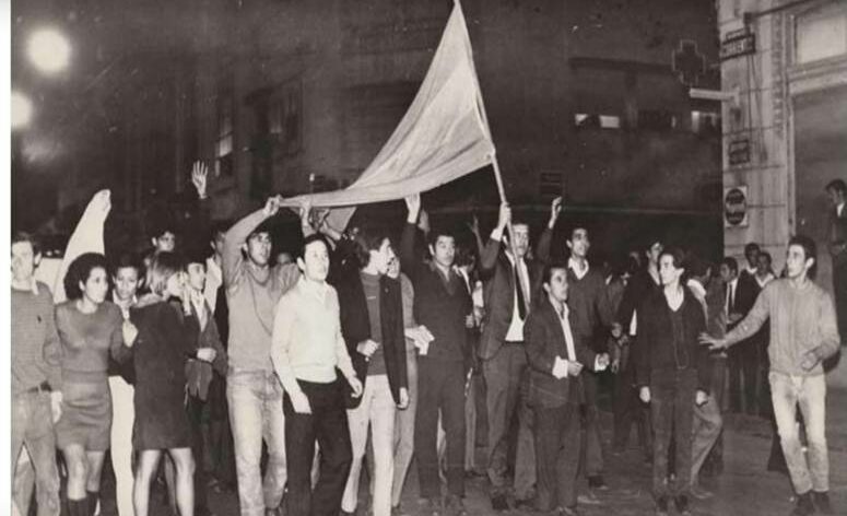Jóvenes marchando por calle Corrientes con una bandera argentina en alto.