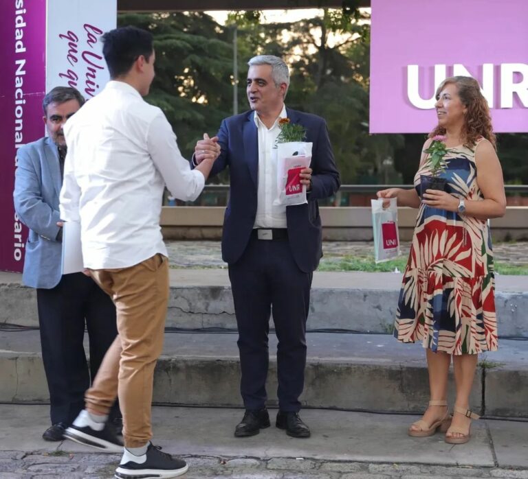 El rector Franco Bartolacci, junto a la coordinadora de gabinete Carina Gerlero, saludan a un estudiante en su graduación.