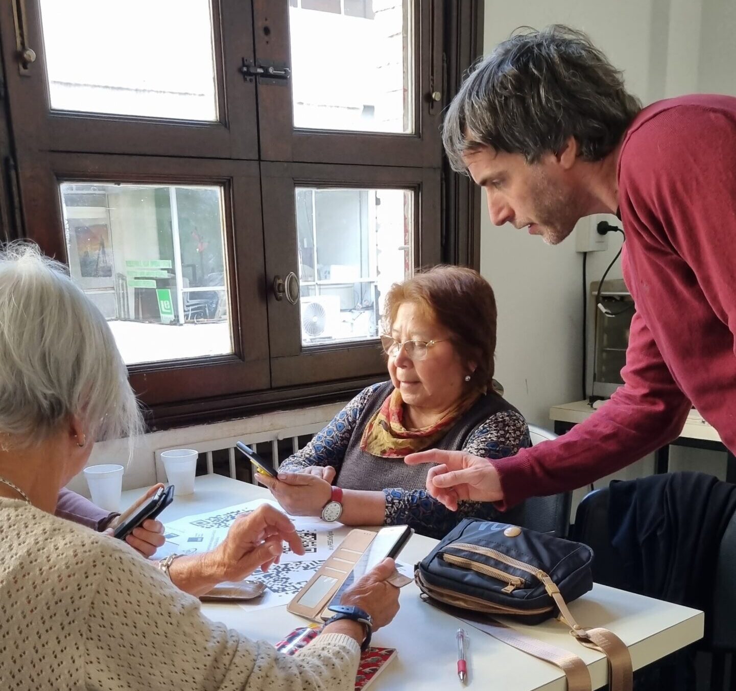 Encuentro de mateada digital donde un estudiante explica una app a dos personas mayores.